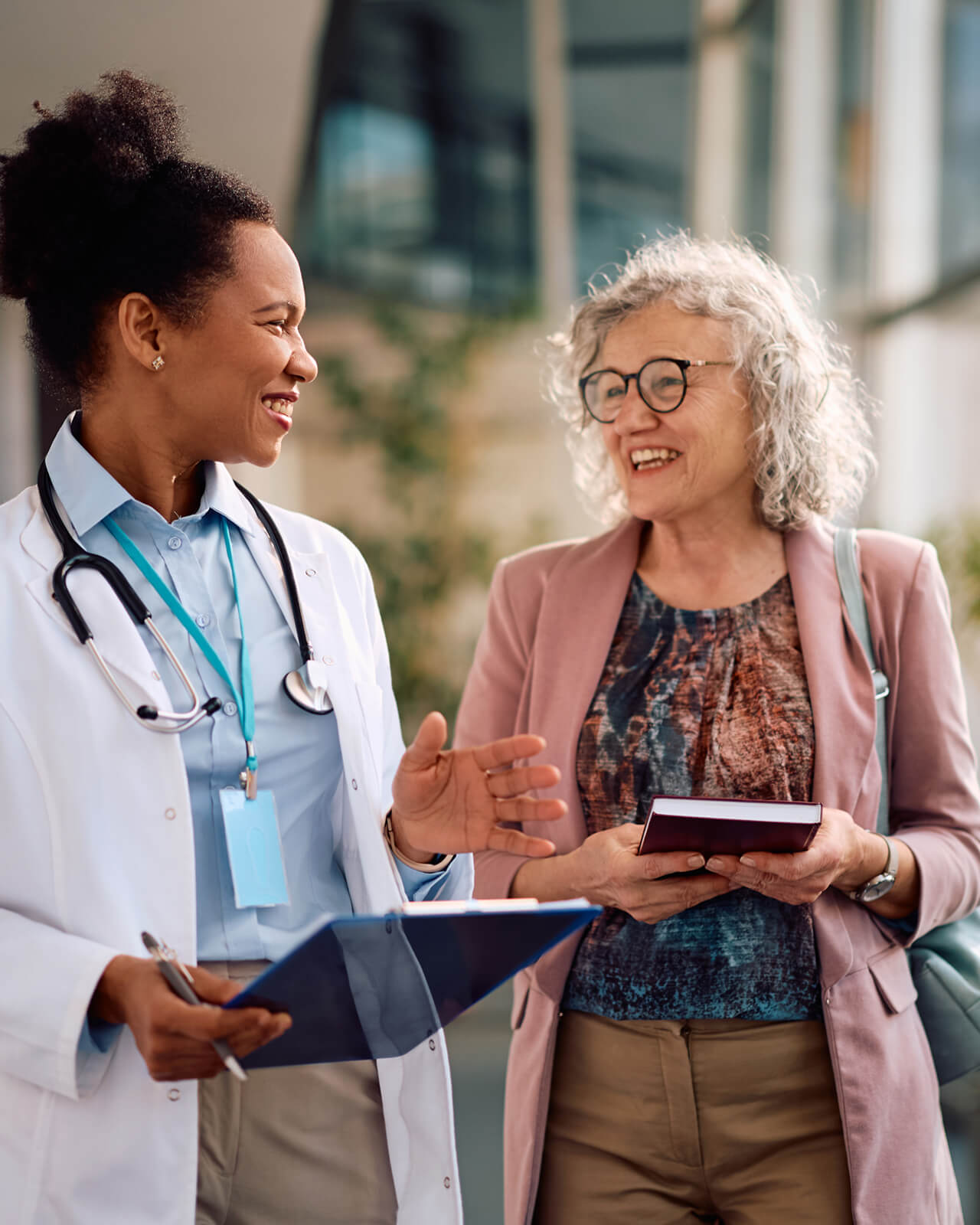 A doctor and patient smiling, walking, and chatting.